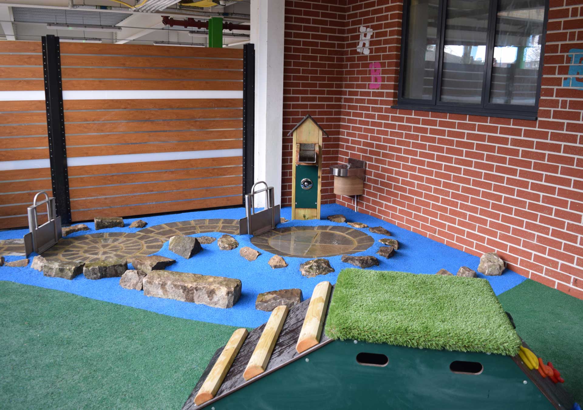 Outdoor play area with a water feature, stepping stones and a mound