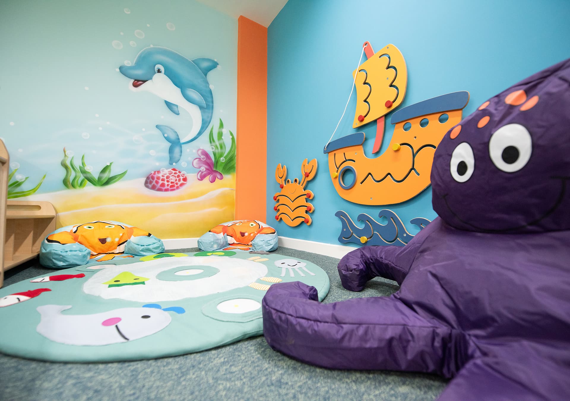 Sea-themed wall mural with a soft octopus toy and cushions