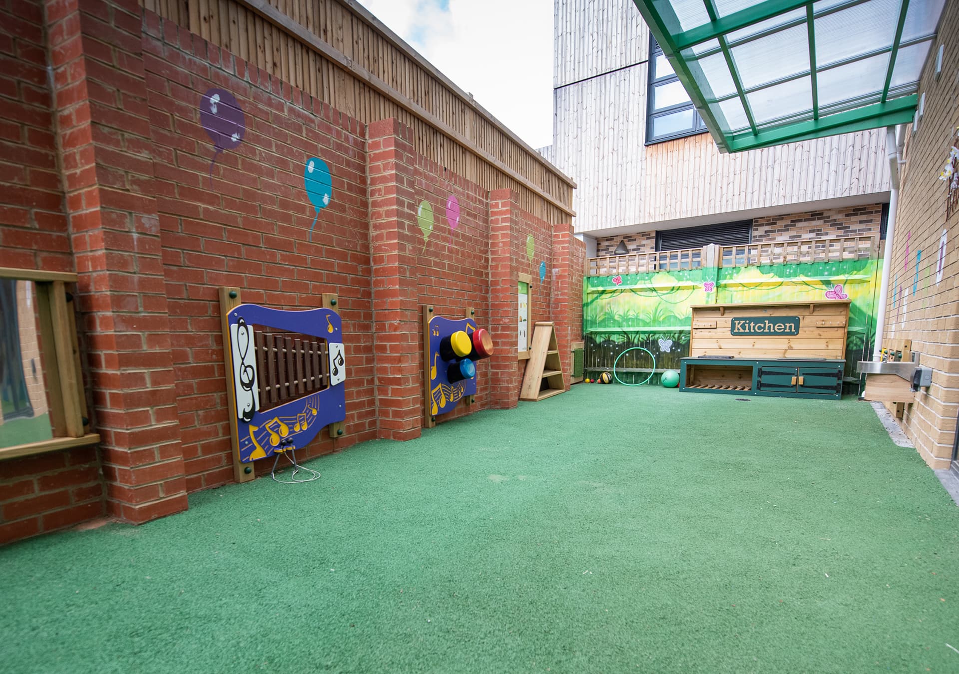 Outdoor play garden with artificial grass and sensory wall panels
