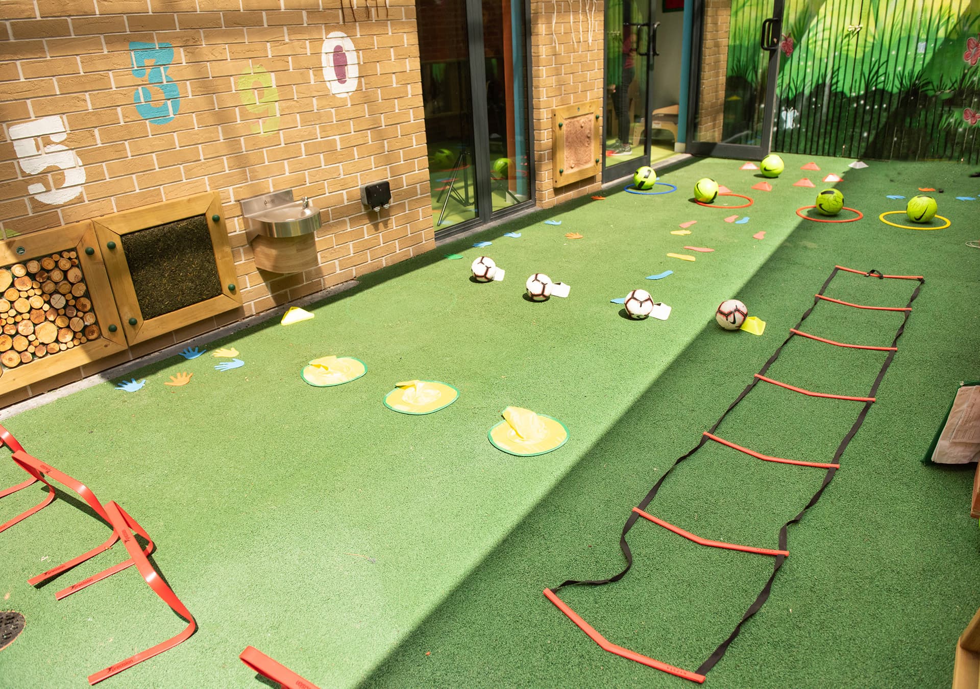 Indoor play area with cones, a ladder and stepping shapes on artificial grass